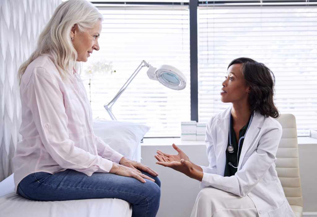 Mature woman patient talking with physician in office